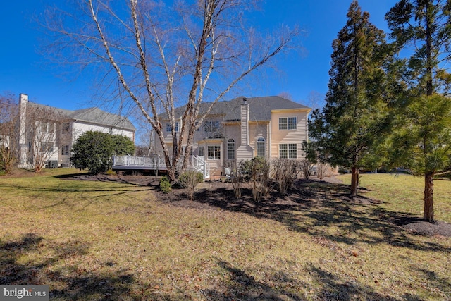 back of property featuring a lawn and a wooden deck