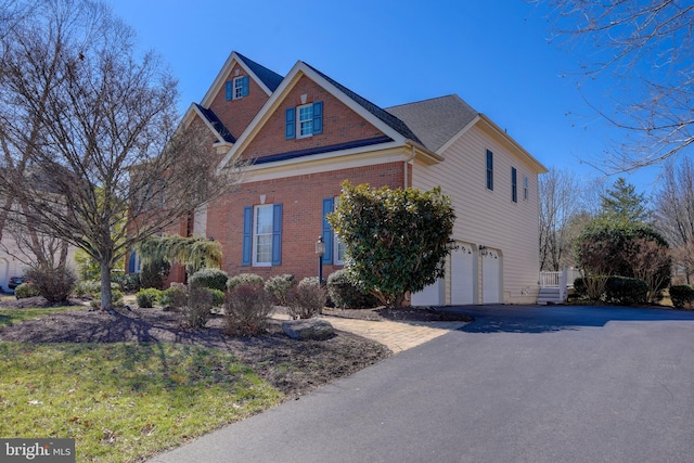 traditional-style home with a garage, brick siding, and driveway