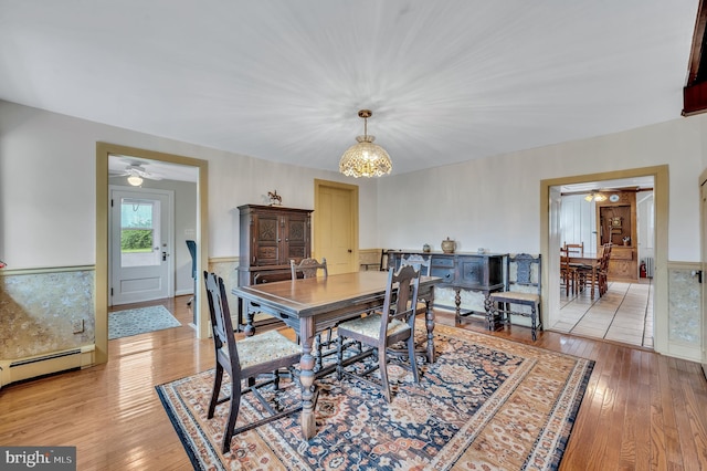 dining area featuring ceiling fan with notable chandelier, light hardwood / wood-style floors, and a baseboard radiator