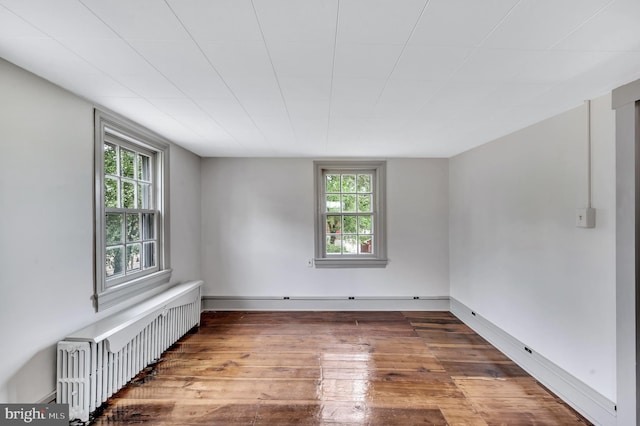 spare room featuring radiator, a wealth of natural light, and wood-type flooring