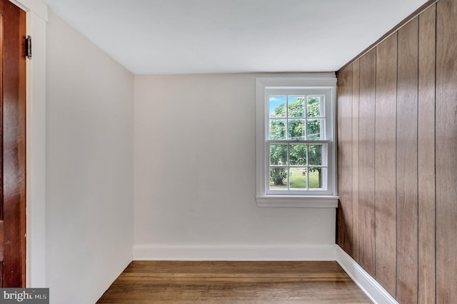 unfurnished room with wood walls and wood-type flooring