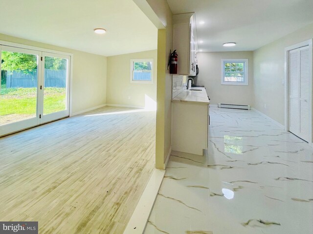 corridor with french doors, a baseboard radiator, light hardwood / wood-style floors, and sink