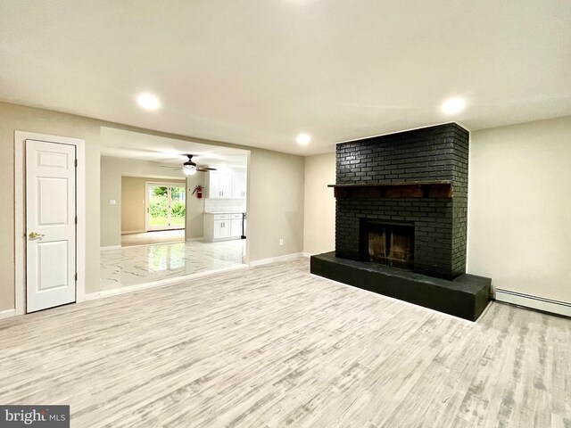 unfurnished living room featuring ceiling fan, light wood-type flooring, a fireplace, and baseboard heating