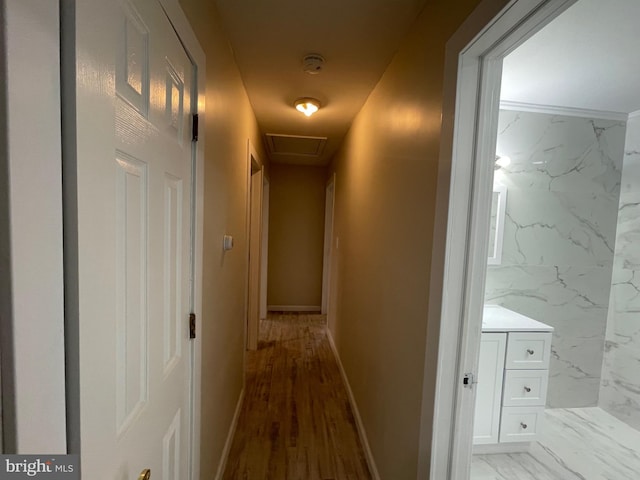 hall featuring light hardwood / wood-style floors, crown molding, and tile walls