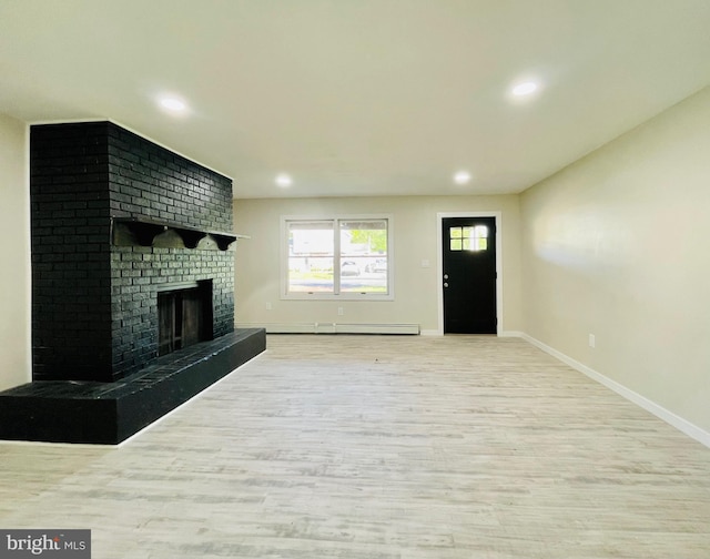 unfurnished living room with light wood-type flooring, a baseboard radiator, and a brick fireplace