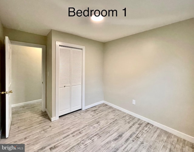 unfurnished bedroom with light wood-type flooring and a closet