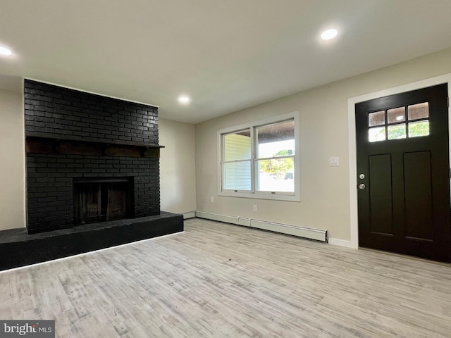 unfurnished living room featuring a fireplace, light hardwood / wood-style floors, baseboard heating, and a wealth of natural light