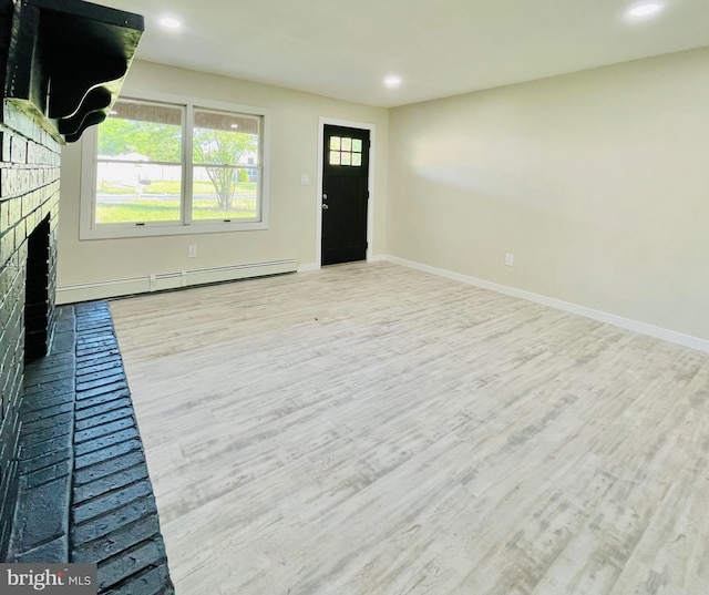 unfurnished living room with a fireplace, a baseboard radiator, and light hardwood / wood-style flooring