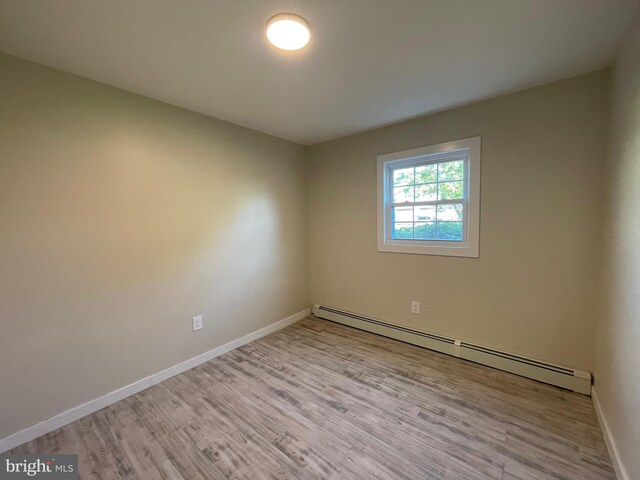 empty room with a baseboard radiator and light hardwood / wood-style flooring