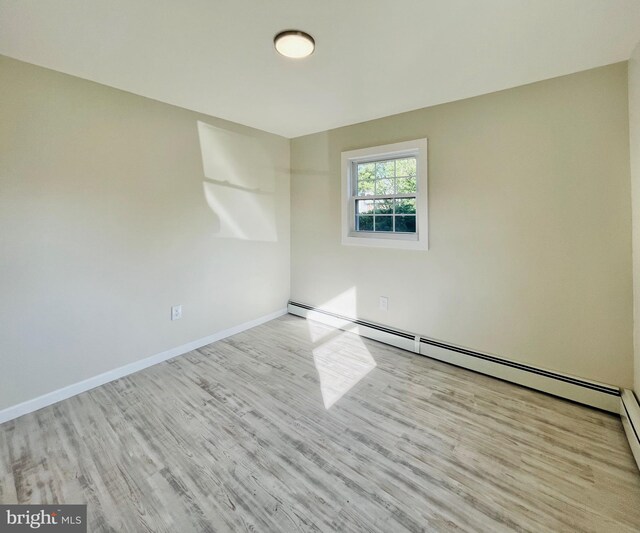 spare room featuring light hardwood / wood-style floors and a baseboard heating unit