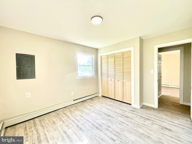 unfurnished bedroom with electric panel, a closet, light hardwood / wood-style floors, and a baseboard heating unit