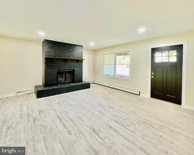 unfurnished living room with baseboard heating, a brick fireplace, and light wood-type flooring