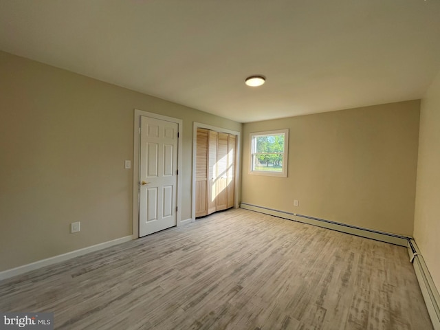 unfurnished bedroom with light hardwood / wood-style flooring and a baseboard radiator