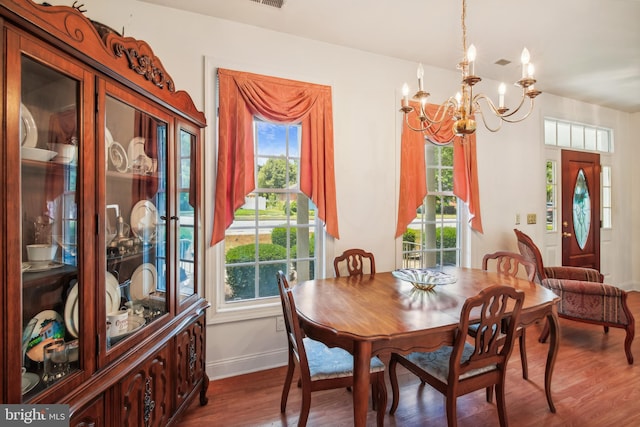 dining room with dark hardwood / wood-style floors, a wealth of natural light, and an inviting chandelier