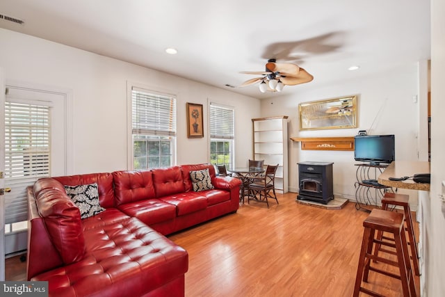 living room featuring hardwood / wood-style flooring, a wood stove, and ceiling fan