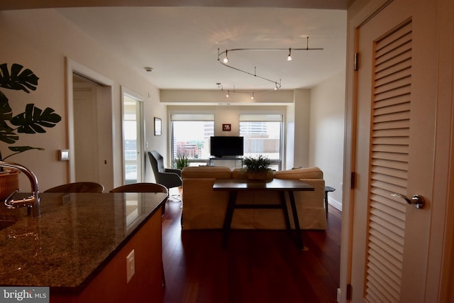 kitchen with dark wood-type flooring, sink, a breakfast bar area, and dark stone counters