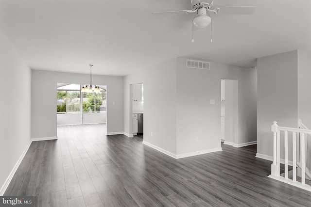 empty room with ceiling fan with notable chandelier and dark wood-type flooring