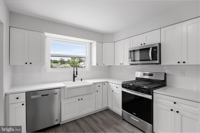 kitchen with backsplash, stainless steel appliances, dark wood-type flooring, sink, and white cabinets