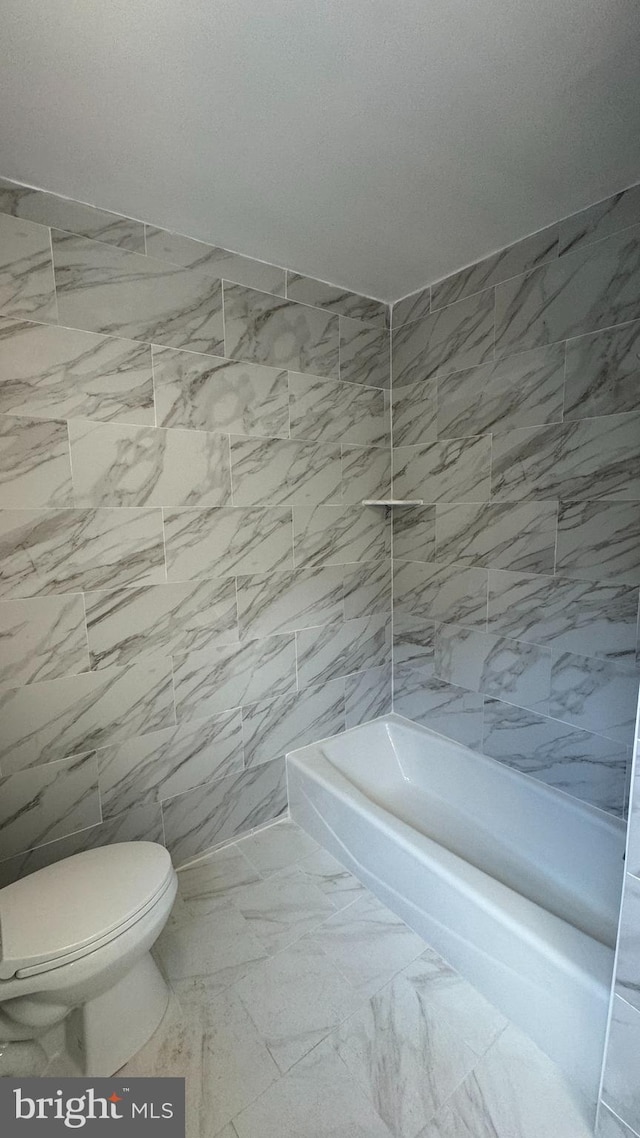 bathroom with shower / washtub combination, toilet, and tile walls