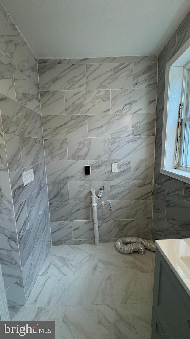 bathroom featuring a tile shower and vanity