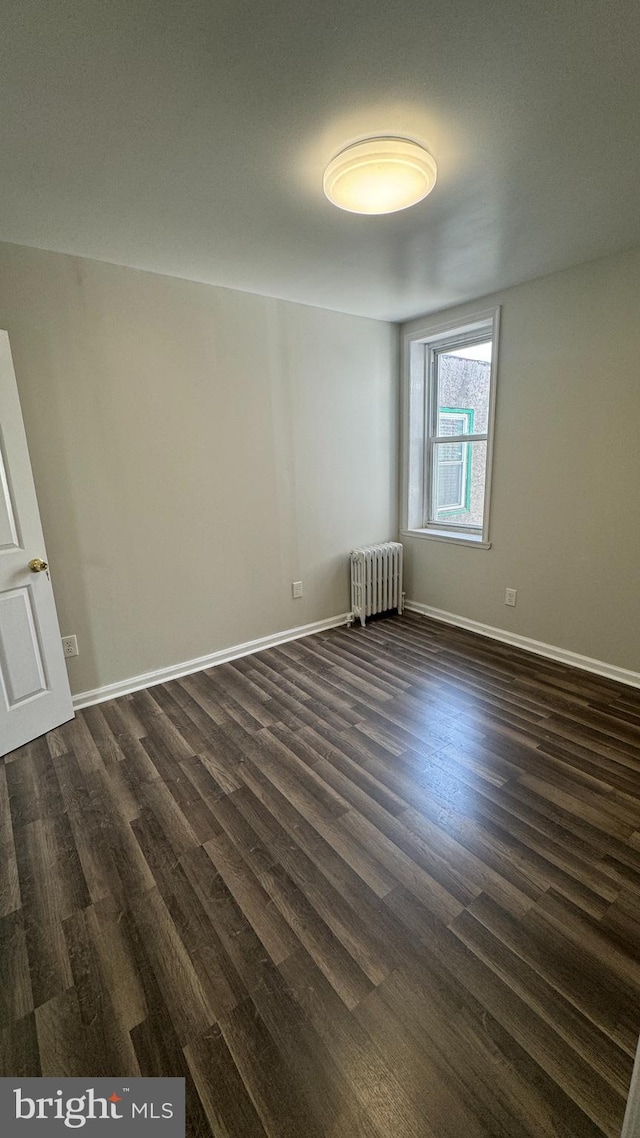 unfurnished room with radiator heating unit and dark wood-type flooring