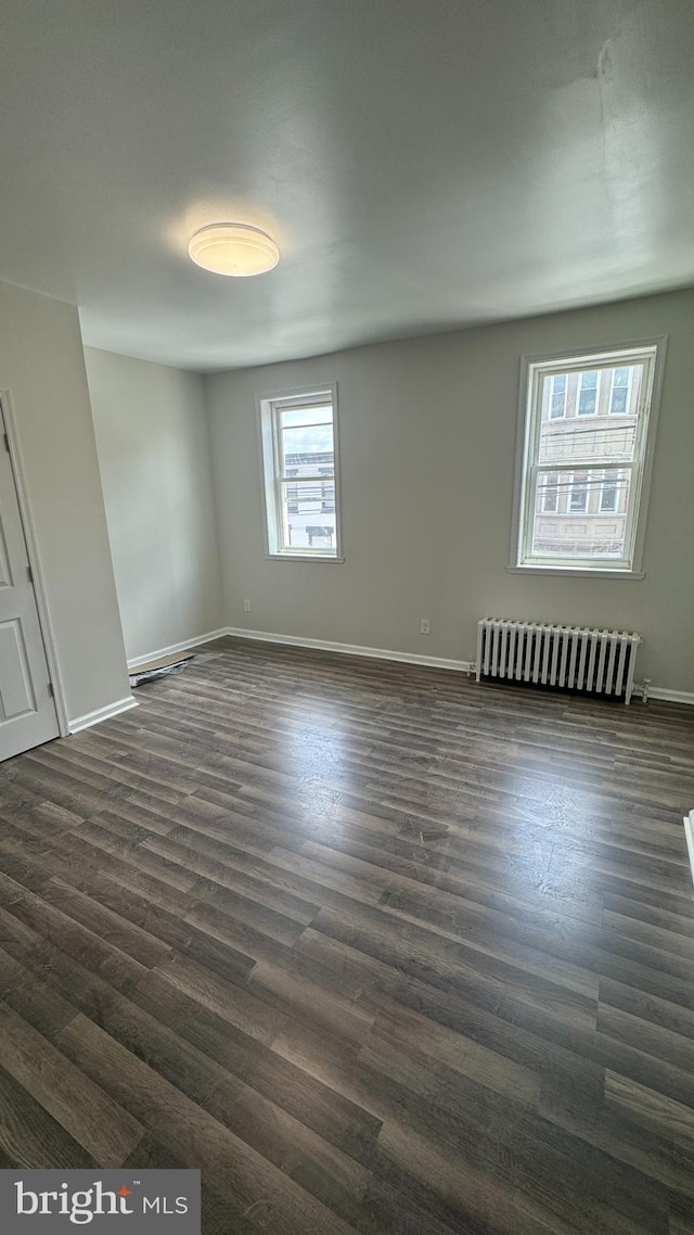 empty room featuring radiator heating unit and dark wood-type flooring