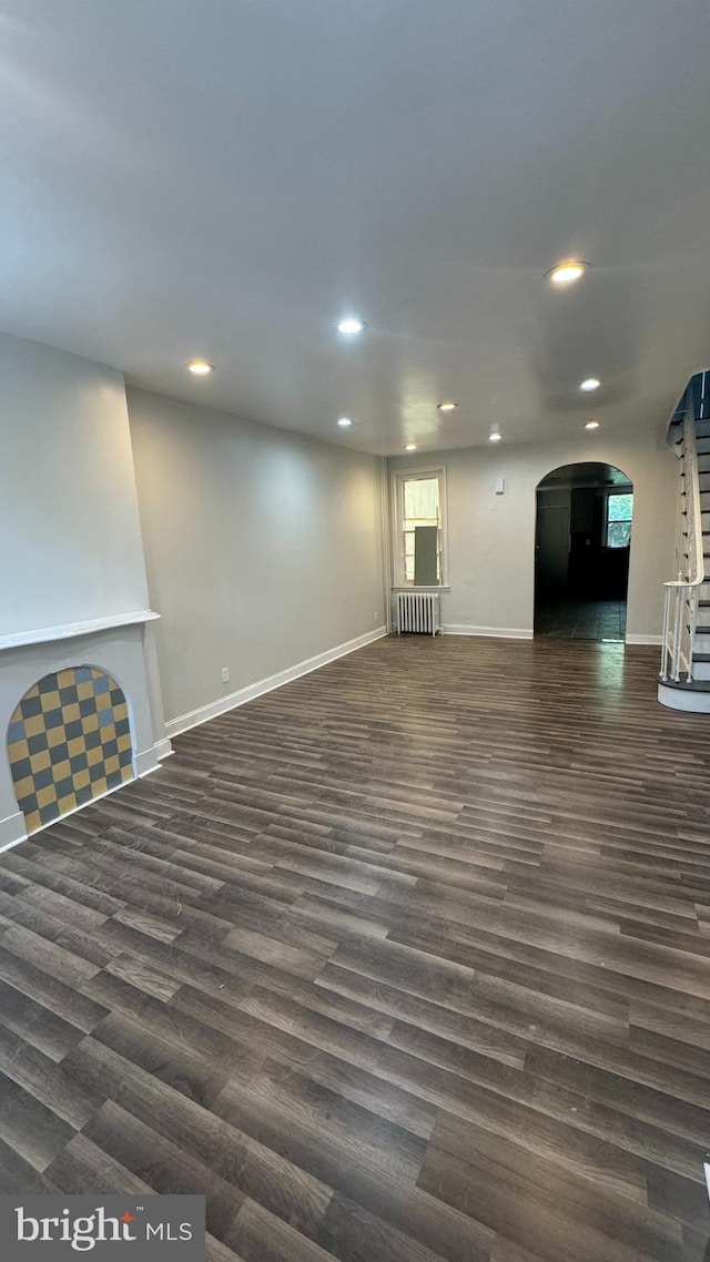 unfurnished living room with radiator and dark wood-type flooring