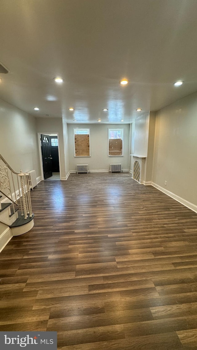 unfurnished living room featuring radiator heating unit and dark wood-type flooring