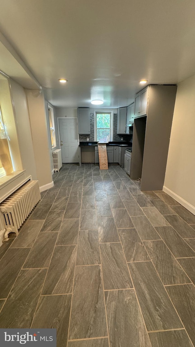 kitchen featuring gray cabinetry, stove, and radiator