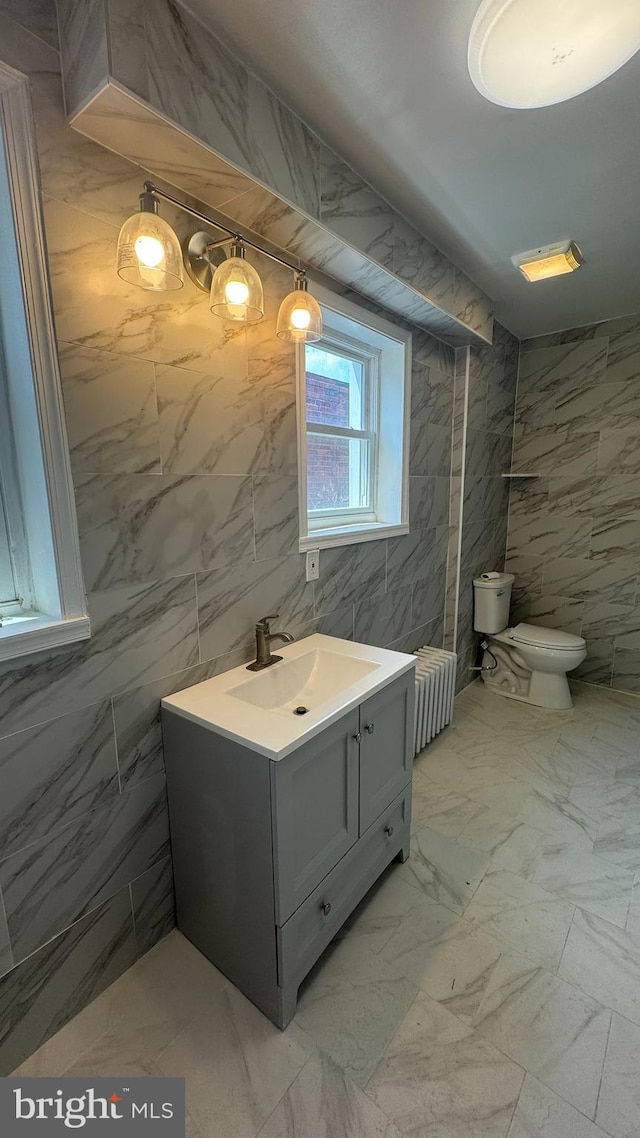 bathroom with radiator heating unit, vanity, and tile walls