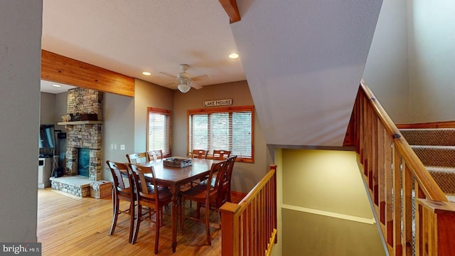 dining room with a fireplace, light hardwood / wood-style flooring, and ceiling fan