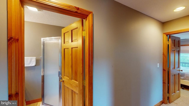 hallway featuring light carpet and a textured ceiling