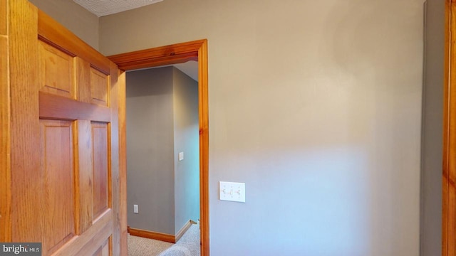 hall with a textured ceiling and light carpet