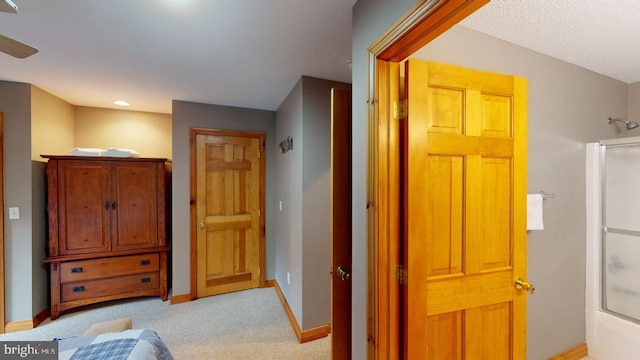 hall featuring a textured ceiling and light colored carpet