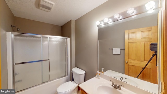 full bathroom with vanity, toilet, shower / bath combination with glass door, and a textured ceiling