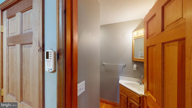 bathroom with a textured ceiling, vanity, and hardwood / wood-style floors