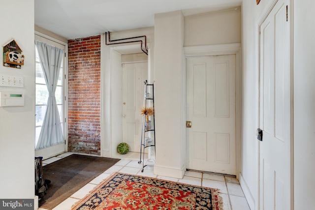 foyer entrance with light tile patterned flooring and brick wall