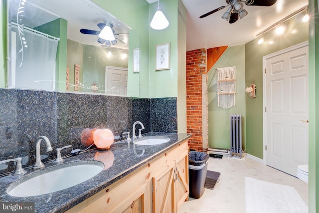 bathroom with tasteful backsplash, radiator, brick wall, vanity, and toilet