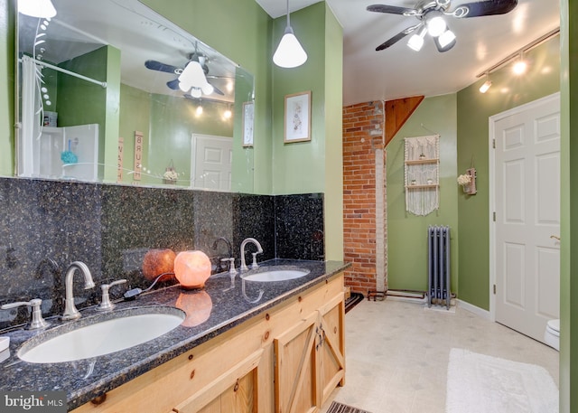 bathroom with decorative backsplash, brick wall, vanity, and radiator