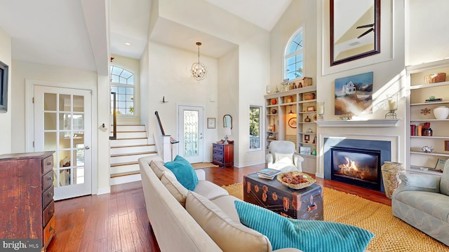 living room with high vaulted ceiling, a healthy amount of sunlight, dark hardwood / wood-style floors, and a notable chandelier