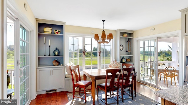 dining room with built in features, dark hardwood / wood-style floors, and a notable chandelier