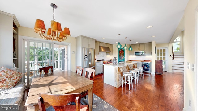 dining room featuring sink, dark hardwood / wood-style flooring, beverage cooler, and an inviting chandelier