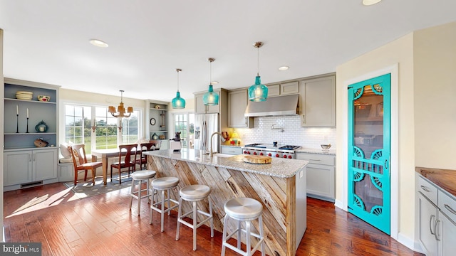 kitchen featuring light stone countertops, dark hardwood / wood-style flooring, a kitchen bar, and an island with sink