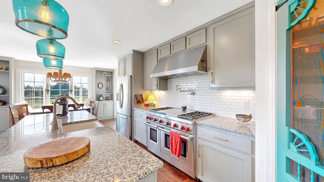 kitchen with stainless steel appliances, extractor fan, dark wood-type flooring, sink, and hanging light fixtures