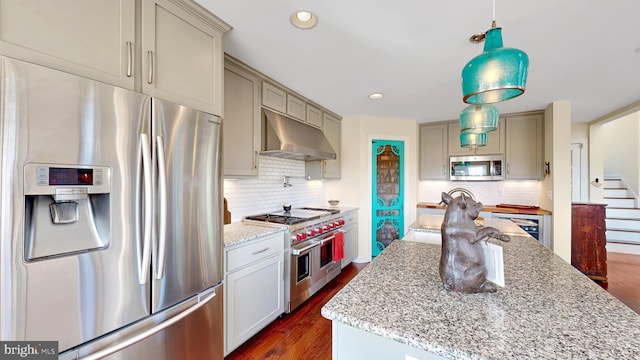 kitchen featuring light stone countertops, stainless steel appliances, dark hardwood / wood-style flooring, ventilation hood, and pendant lighting