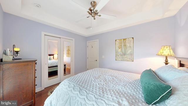 bedroom featuring hardwood / wood-style floors, a tray ceiling, and ceiling fan