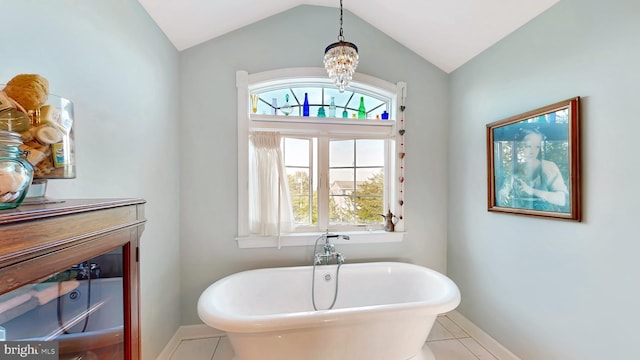 bathroom featuring lofted ceiling, a washtub, a notable chandelier, and tile patterned flooring