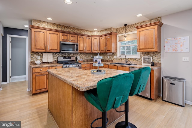 kitchen with a breakfast bar, stainless steel appliances, sink, light hardwood / wood-style flooring, and a kitchen island