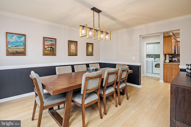 dining area featuring washer and dryer, light wood-type flooring, ornamental molding, and a notable chandelier