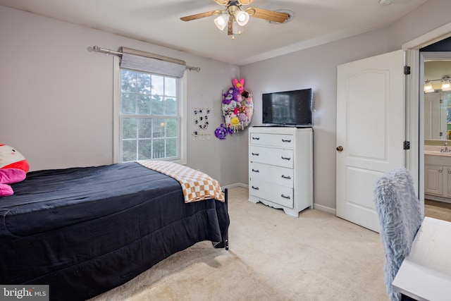 bedroom featuring ceiling fan, ensuite bathroom, and light colored carpet